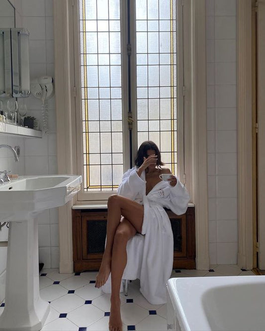 woman holding tea cup wearing bathrobe in white bathroom
