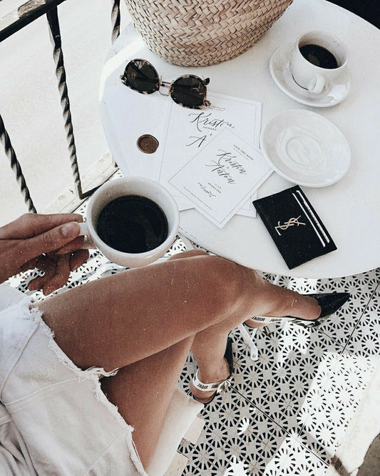 woman with chanel shoes and save the dates at cafe having coffee