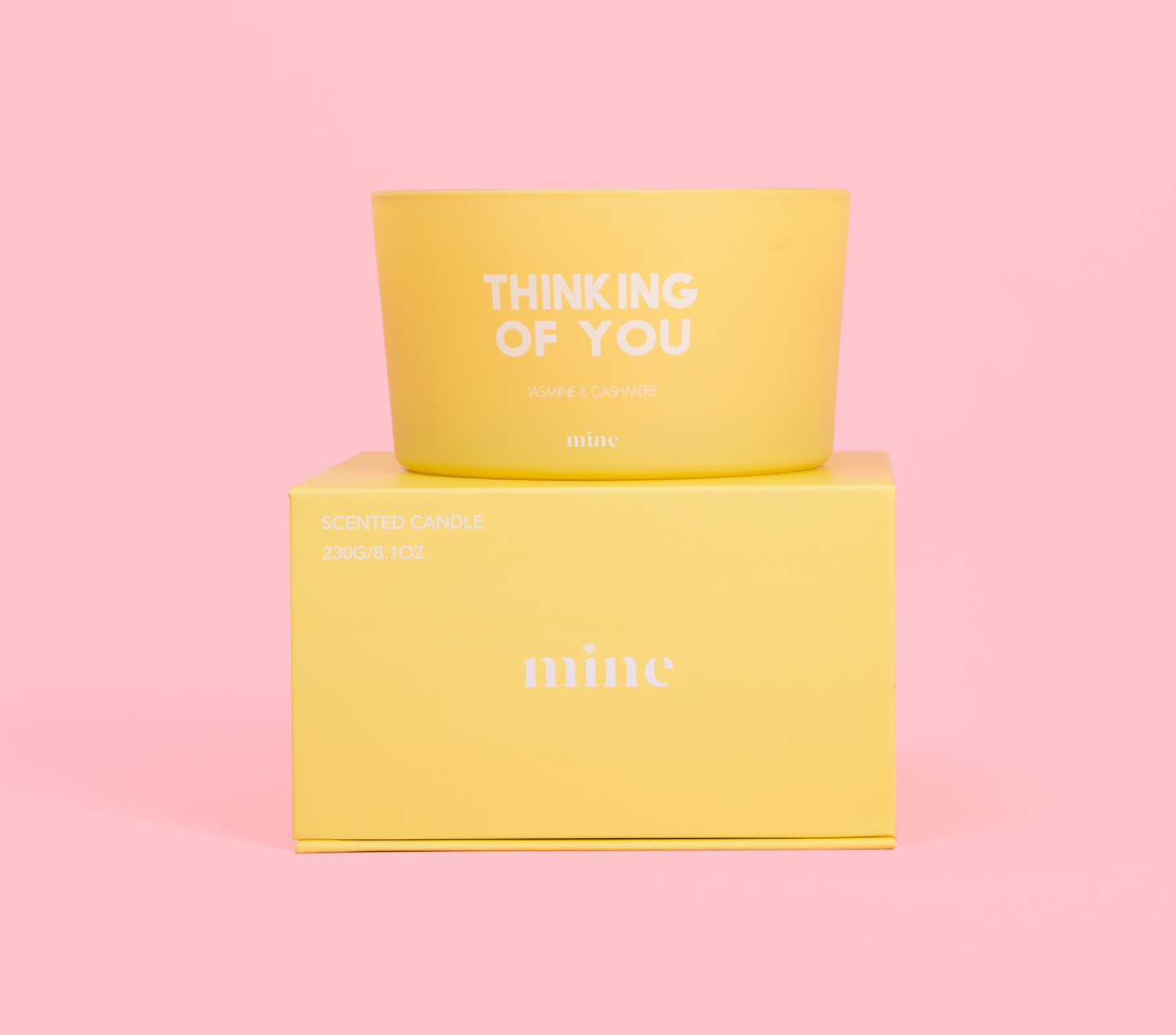 yellow round circular candle that says Thinking of You on top of yellow gift box on pink background