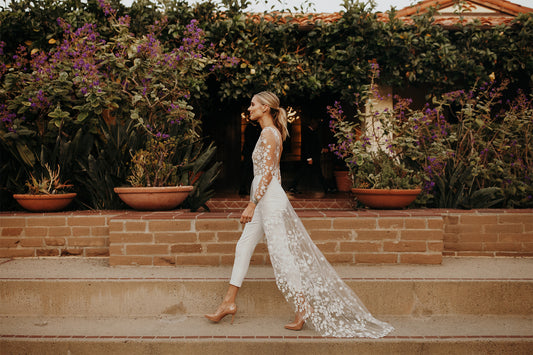 blonde woman in white wedding lace jumpsuit with train