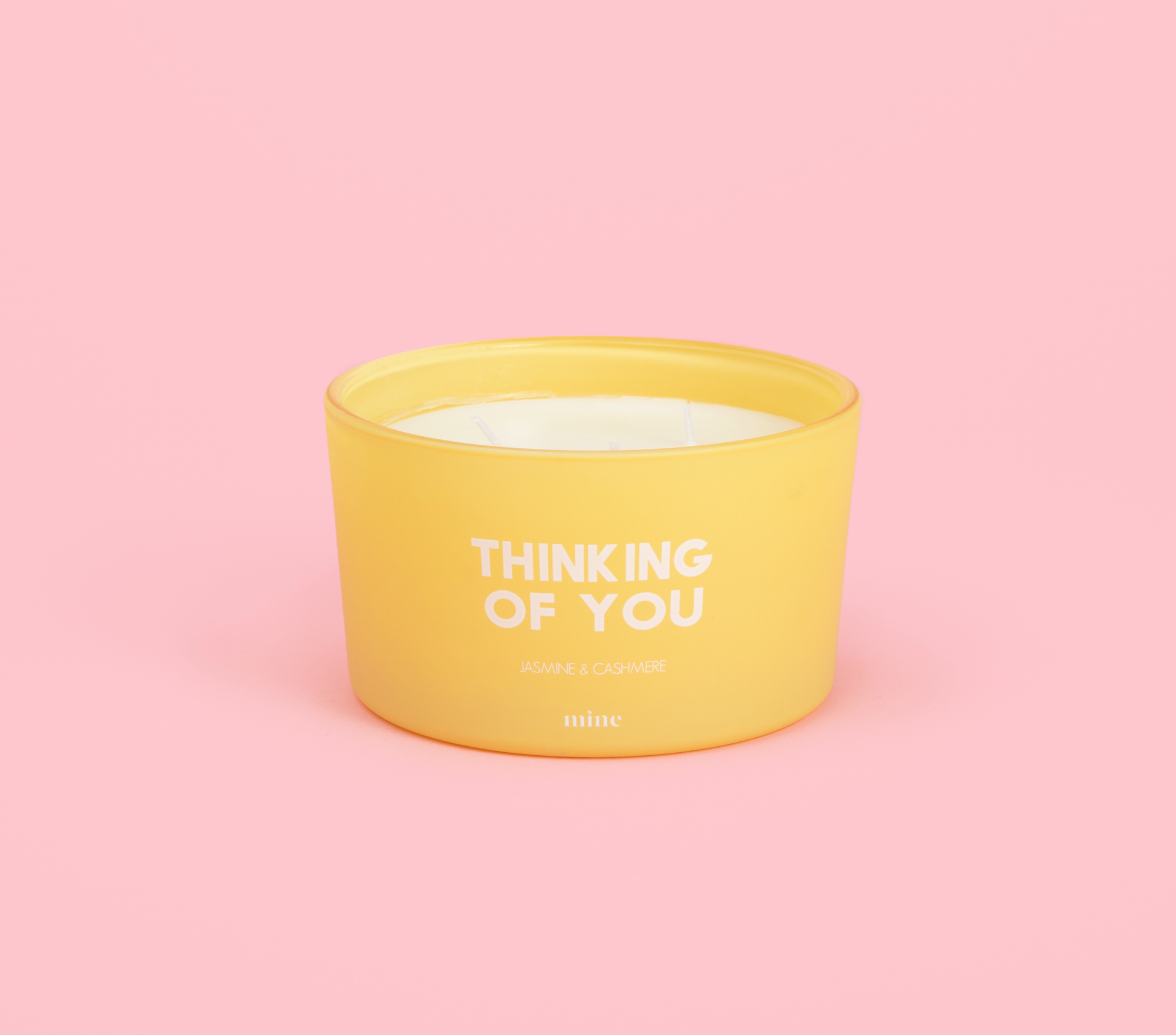 yellow round circular candle that says Thinking of You on pink background