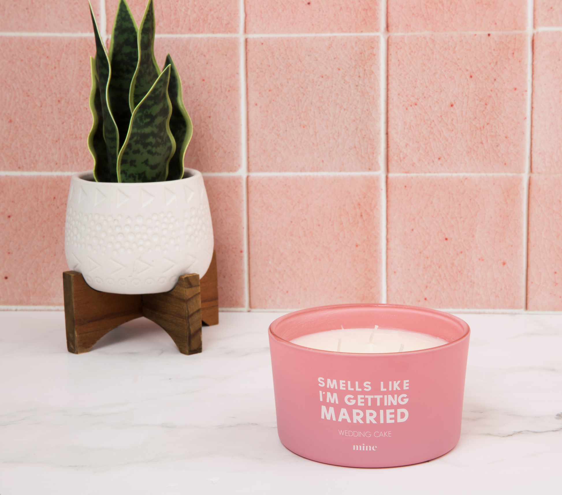 Wedding Cake Candle - The Mine Company - Smells Like I'm Getting Married - Pink Bride Candle on white marble next to succulent plant against pink wall